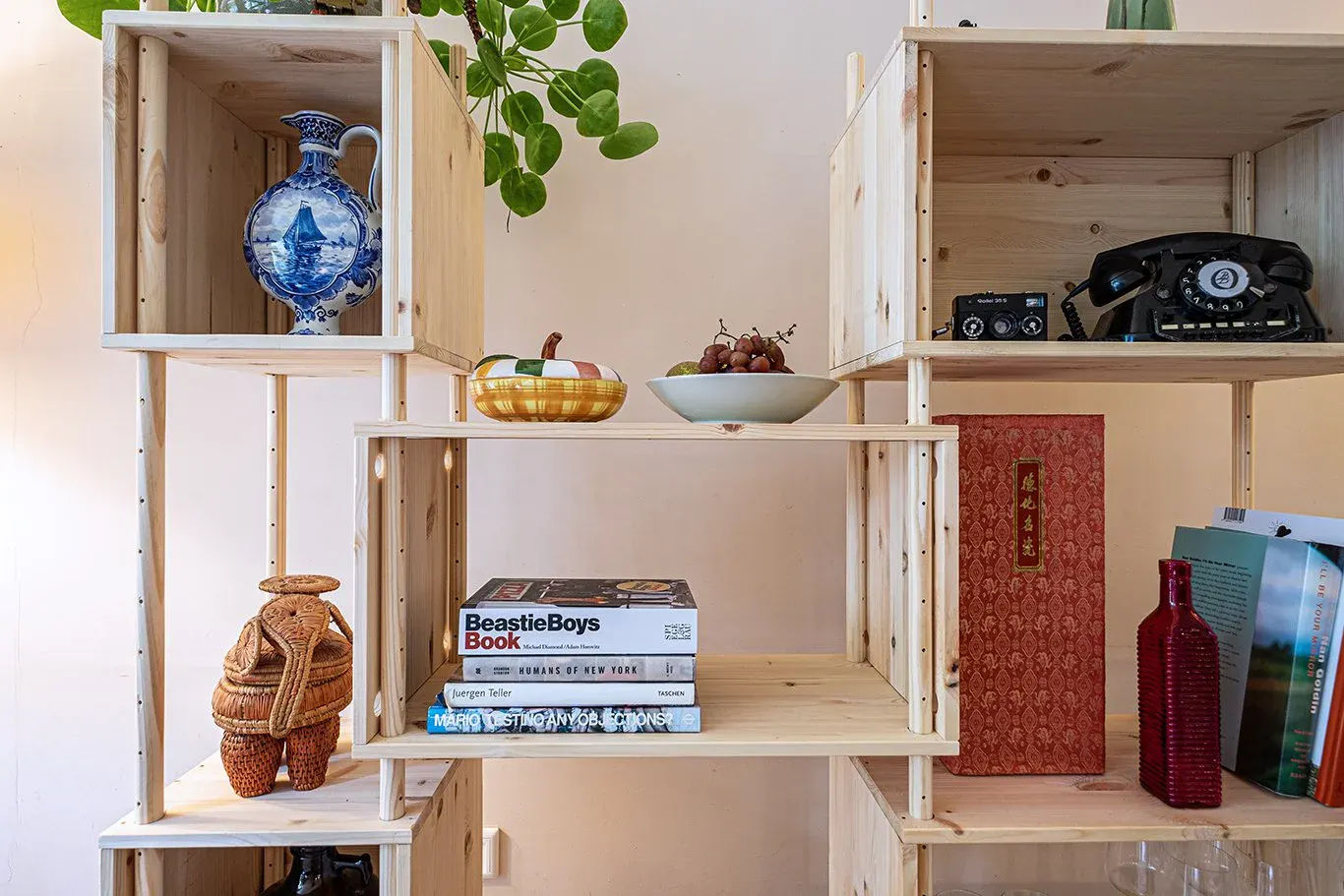 Detail of filled RMC shelves: a delft blue jug, a bowl of grapes, art books and an old telephone
