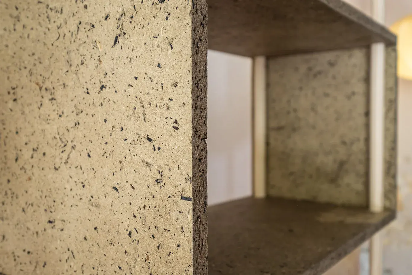 Close-up of a speckled biobased box in the cabinet, its pressed fibre edge in full view