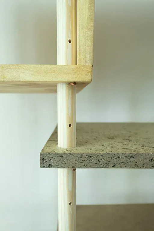 Detail of a speckled biobased shelf resting on a drilled pine pole